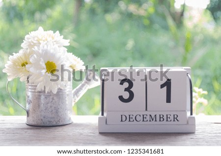 Close up of wooden calendar date December,31 with flowers in vase on wooden and blurred background,soft focus,this image for happy new year concept.