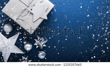 Merry Christmas and Happy Holidays greeting card, frame, banner. New Year. Noel. Silver Christmas gifts, ornaments on blue background top view. Winter holiday xmas theme. Flat lay.