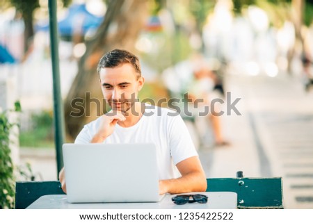 Confident young man working on laptop computer while sitting outdoors