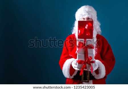 Santa holding Christmas gift boxes on a dark blue background