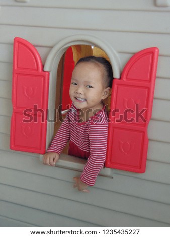 Cute Asian girl wearing a red and white shirt playing toys on the playground.