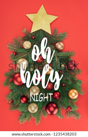 top view of pine tree branches, golden star and christmas balls arranged in christmas tree isolated on red with "oh holy night" inspiration 