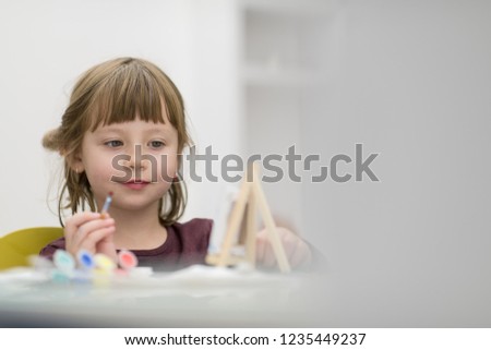 happy little girl painting on canvas image at home