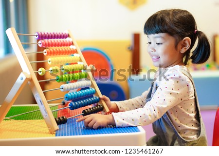 Cute Asian little kid girl playing with abacus at home. Smart child learning to count. learning, classroom, lesson concept.                       Royalty-Free Stock Photo #1235461267
