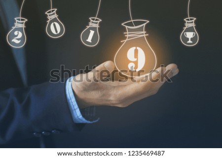 Businessman hand holding money bag with welcome year 2019 on dark background