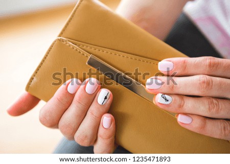 A young girl with beautiful white manicure holds a black briefcase. Style of fashion