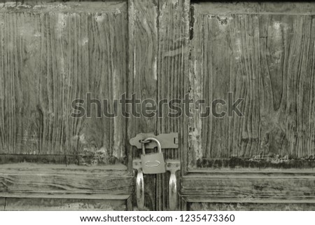A wood door locked by old style pad locked. Sepia color for vintage style concept. Royalty-Free Stock Photo #1235473360