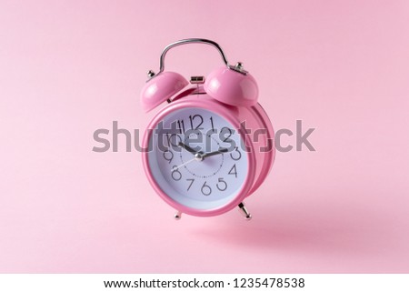 Pink alarm clock on pastel pink background. Minimal concept.