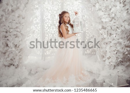 Portrait of beautiful child girl with long hair in white dress holding lantern, concept christmas.