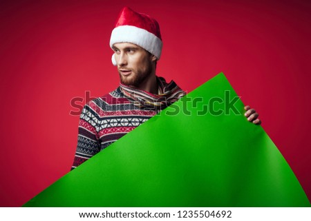 man holds green mocap on a red background                 