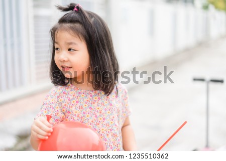 4 year old little asian girl blowing a balloon.