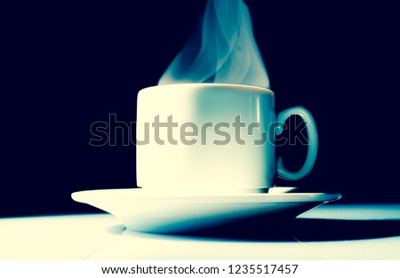 Cup of coffee with a beautiful smoke steam fume close-up on a black background. Vintage, grunge old retro style photo.