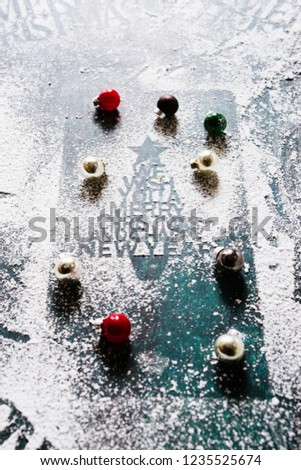 Christmas celebration greetings stenciled with confectionary sugar  and little colored christmas balls, over a rusty blue background