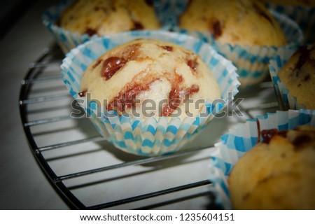 Low muffins with chocolate baked from young confectioner in learning in blue and white basket.