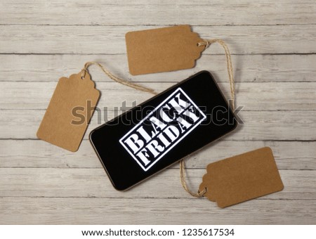Price tags and phone with the inscription black friday on a wooden background, the concept of sales