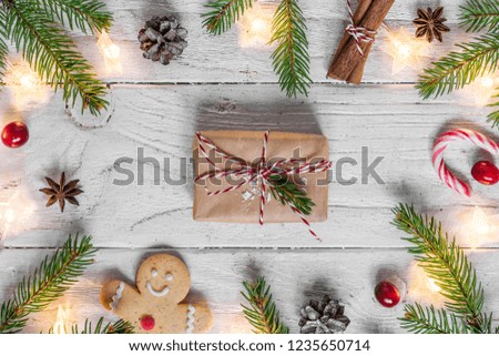 Christmas background with christmas lights, food, fir tree, berries, gift box and pine cones on white wooden table. top view. flat lay