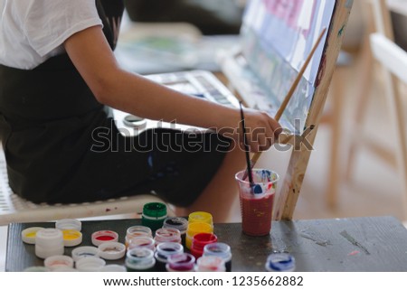 Little girl painting a picture in a studio or art school. Creative pensive painter child paints a colorful picture on canvas in workshop.