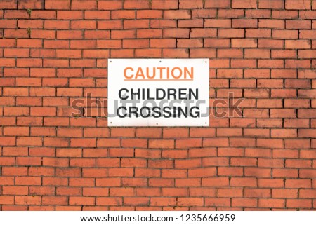Caution children crossing road safety sign on school wall