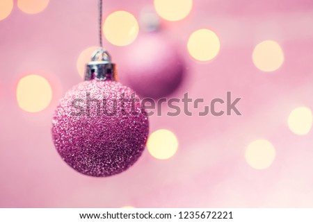 Photo of two New Year's pink balls on pink background with spots.