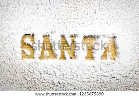 Santa name written in the snow revealing a wood texture background