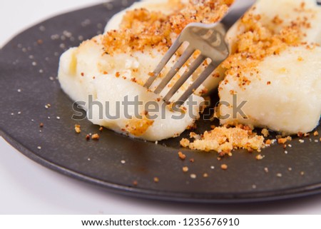 Dumplings with cottage cheese (traditional polish dish called lazy pierogi/ leniwe pierogi) fried with bread crumbs and sprinkled with sugar, eaten with a fork