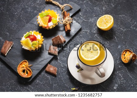 Cup of tea and cookies on black stone background.