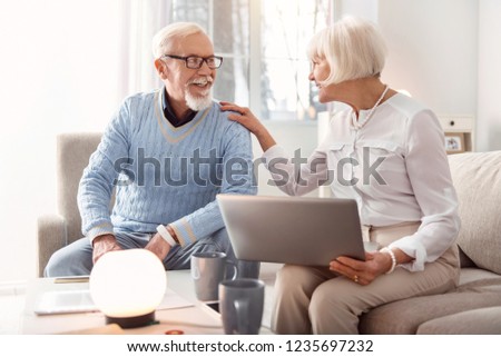 Purchasing process. Nice mature couple sitting on the sofa in the apartment while discussing online purchase