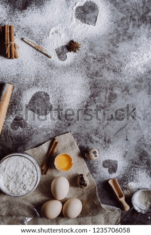 Healthy baking ingredients. Background with flour, rolling pin, eggs, and heart shape on kitchen gray kitchen table.  Top view for Valentines day cooking. Copy space.