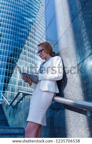 A beautiful girl standing in the center of the city holding a laptop in her hands