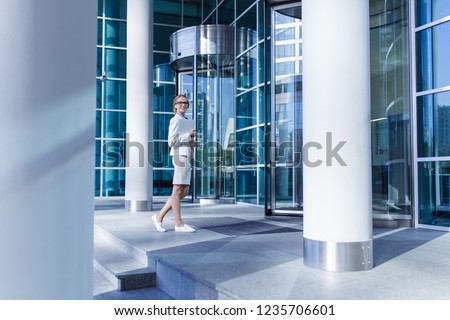 Pretty young woman standing in front of revolving door