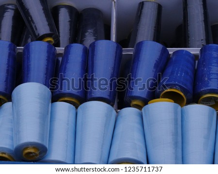 Gran rolls, partly covered with dust, in shades from light blue to dark blue, stored in a plastic box. raw material for handicraft textile work and hobby