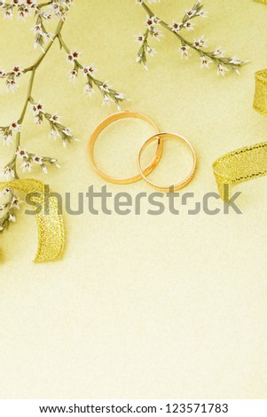 Gold wedding rings and branch flowers. Holiday postcard yellow textured old paper