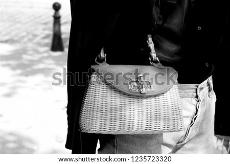 Stylish Parisian Lady with Wicker Handbag, wearing Vintage Blue Jeans, Black Jacket. Elegant Parisian walking the street of Paris, France. Street Style Fashion Photography.