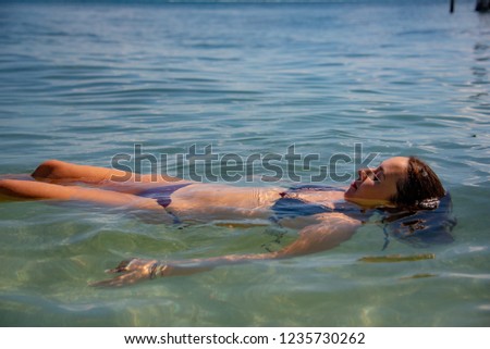 Side view of a young beautiful woman relaxing in the shallow water of the Carribean Sea during summer vacation in Cancun, Mexico