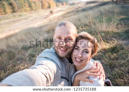 Happy middle age couple make selfie in the autumn forest in Russia. They smiling and looking to camera.
