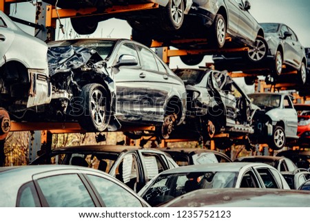 Damaged cars waiting in a scrapyard to be recycled or used for spare part Royalty-Free Stock Photo #1235752123