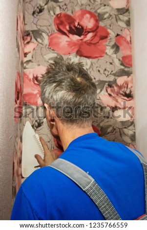 Repair or reconstruRepair or reconstruction. Worker attaches Wallpaper to the wall.