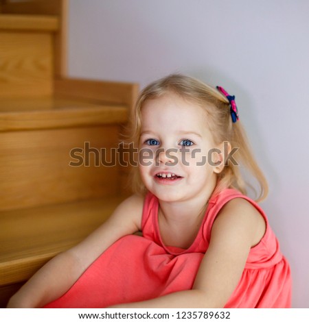 Portrait of little cute girl smiling on stairs in cozy room