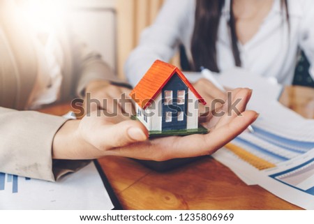 Real estate services for buying home holds house model and calculating table payment to customer. Royalty-Free Stock Photo #1235806969