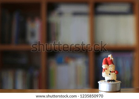 Little snowman on the table in the library. Bookshelf is the background
