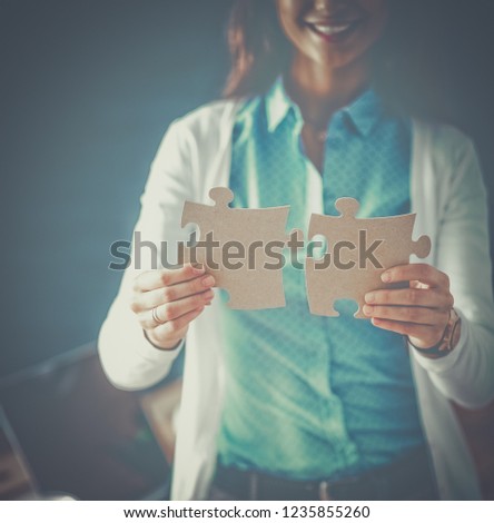 Business woman holding and pointing to a puzzle piece