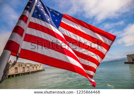Alcatraz tour to Alcatraz island by boat trip in San Francisco Bay, California, United States. Ferry boat with American flag waving in San Francisco pier.