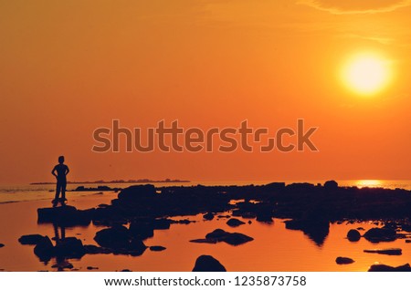 silhouette of a woman at sunset-an evening walk along the summer shore
