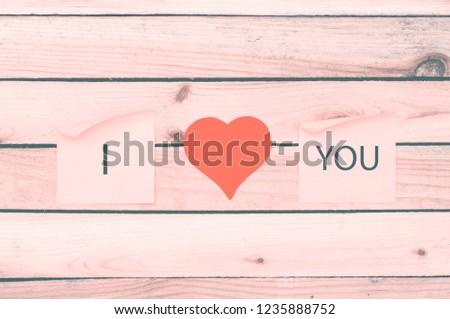 Red heart and sticker in pink soft light on wooden background. I love you. 