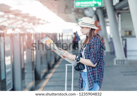 Asian traveler look at the map and waiting Bangkok Mass Transit System Public Company Limited on station, Woman backpacker find travel place in Bangkok, Thailand 