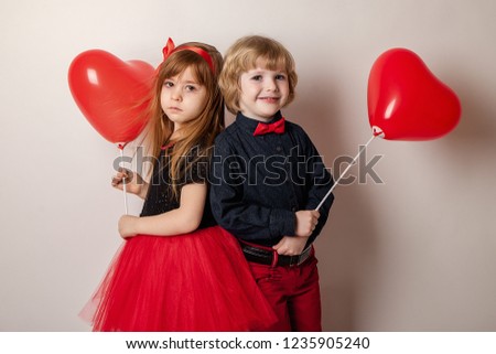 The first love. romantic boy and little girl in red with balloons in the form of red hearts on a white background