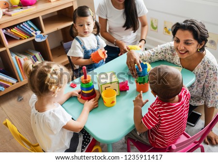 Nursery children playing with teacher in the classroom Royalty-Free Stock Photo #1235911417