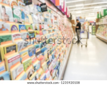 Blurred motion customer with shopping cart browsing greeting cards at retail store in Texas, America.