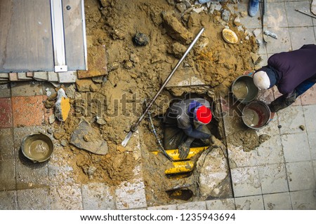 Technician worker is repairing the underground water pipe broken. Unidentified plumber is digging for repair the underground pipe cracked. Royalty-Free Stock Photo #1235943694