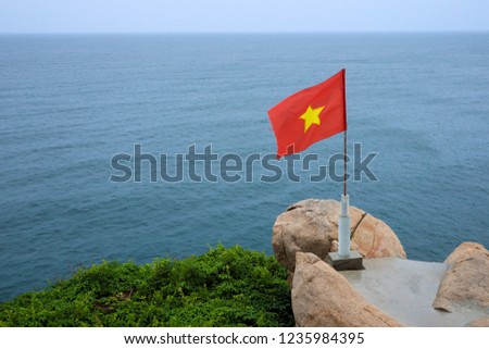 A Vietnamese flag fluttering towards the blue sea that looks really beautiful. Pictures were taken from the island of Binh Hung, Khanh Hoa, Cam Ranh province, Vietnam.